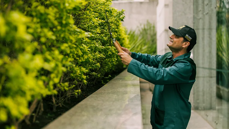 Jardineiro do Grupo Belfort fazendo a manutenção de área verde em condomínio